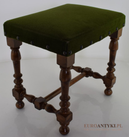 Mały rustykalny stołek obity zielonym materiałem.