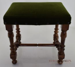 Mały rustykalny stołek obity zielonym materiałem.